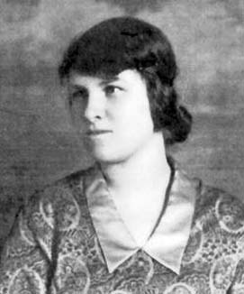 Young woman with dark hair and a squint