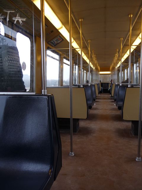 Empty tram interior viewed to the rear, a few people at the end