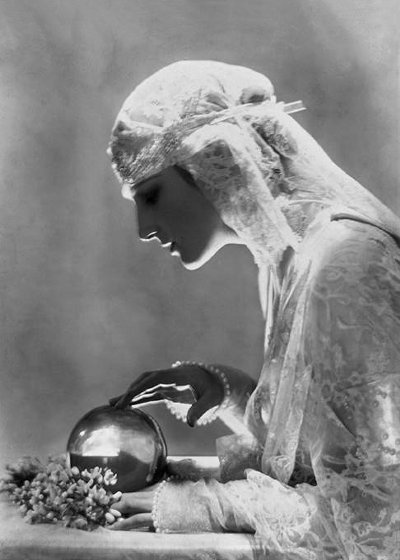 Psychic medium in white, touches and observes her crystal ball